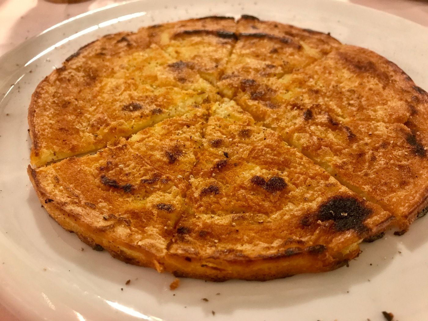 Farinata dorata e croccante, tagliata a spicchi su un piatto bianco