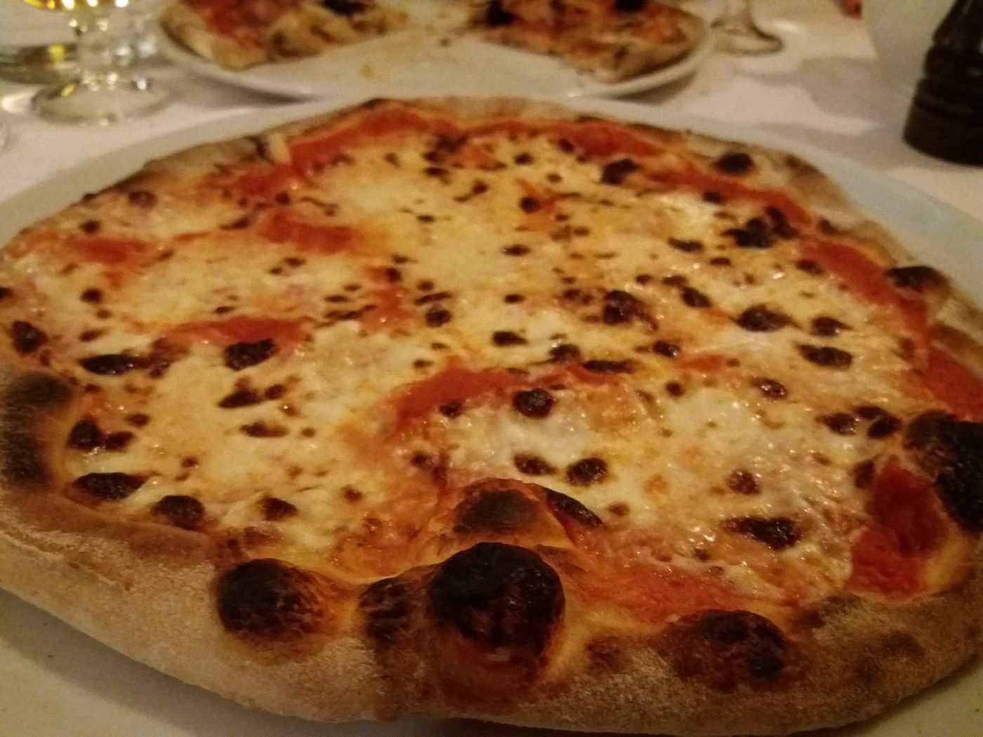Pizza margherita appena sfornata, con il bordo maculato dalla cottura nel forno a legna