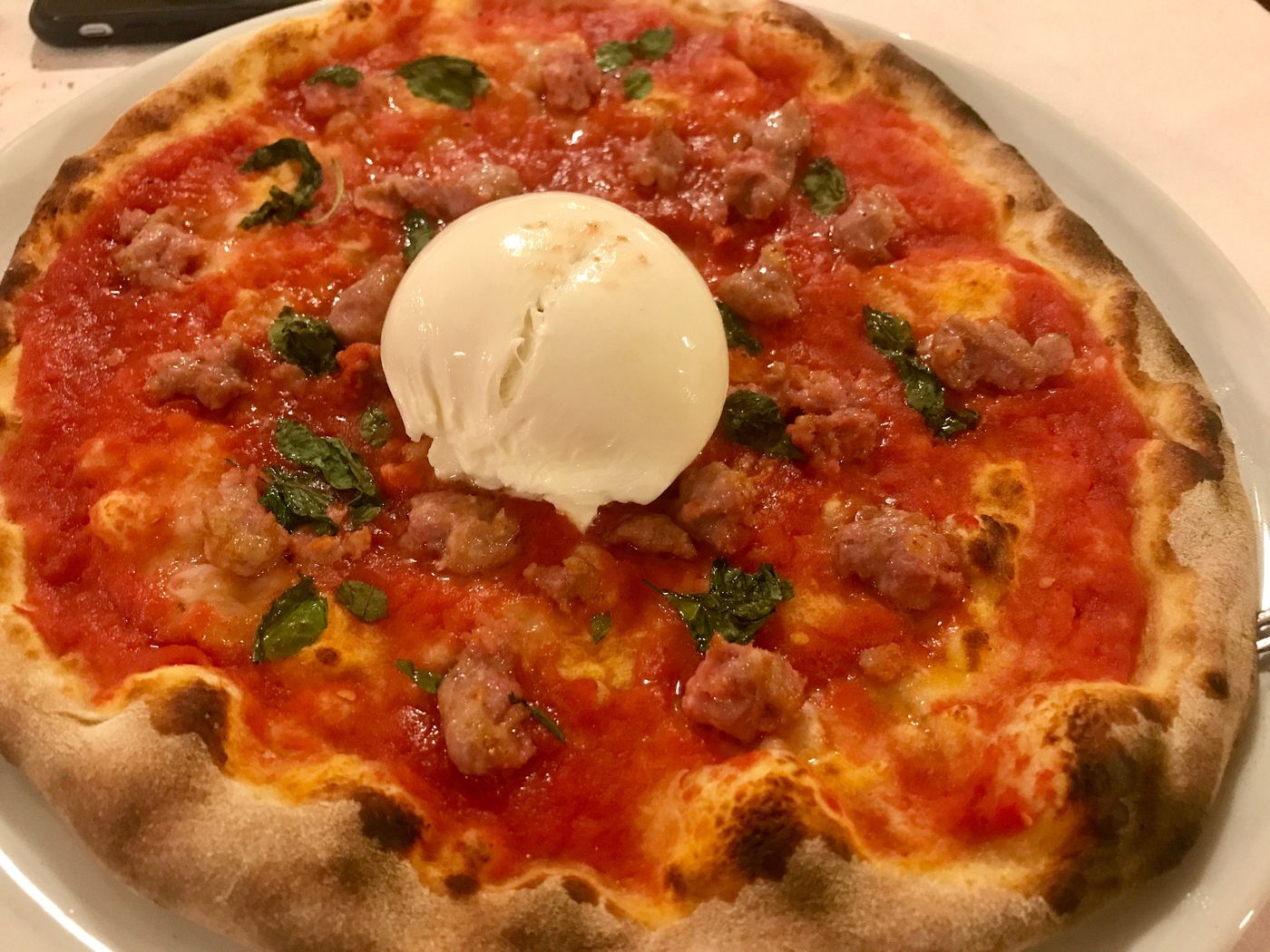 Pizza rossa con salsiccia sbriciolata, basilico e una burrata intera al centro